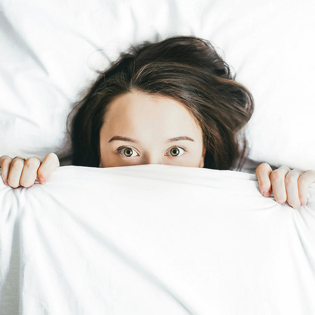 Woman in bed with white sheets, relaxing and ready for a good sleep experience